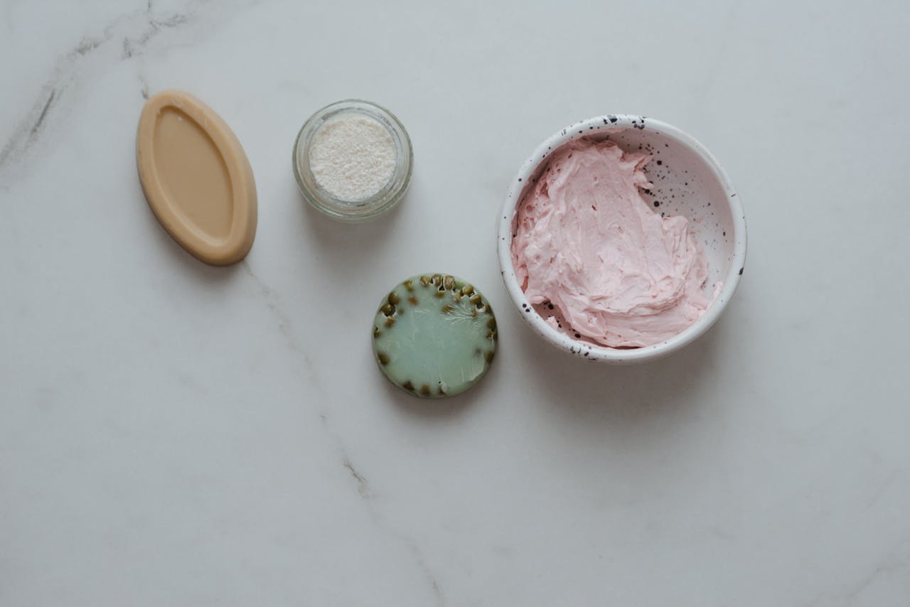 A minimalist flat lay of beauty products on a marble surface featuring creams and soaps.