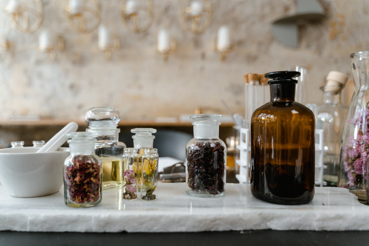 Aesthetic display of essential oils and dried flowers in glass bottles for aromatherapy use.